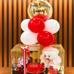 Birthday Charm Box with cake, red roses, teddy bear, KitKat chocolates, balloons, greeting card, and acrylic gift box.